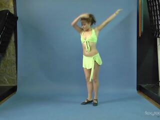 Klocka mila gimnasterka spridning henne benen och göra yoga exercises